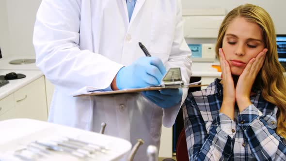 Dentist preparing dental report of female patient