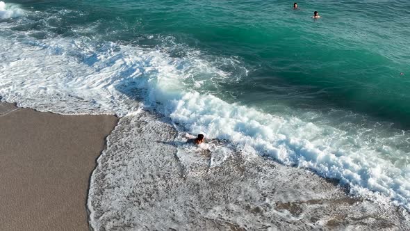 A young girl happily fights with the waves aerial view 4 K