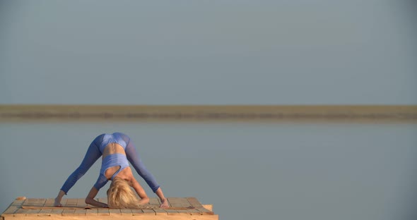 Sexy Young Woman in Blue Sportswear is Stretching in the Middle of the Lake