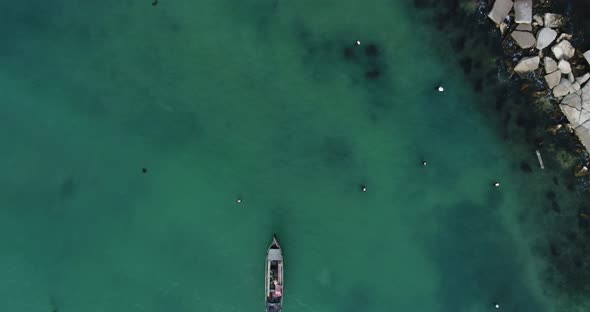 Top down view of lonely fishing boats and wooden pier in turquoise ocean, sea.