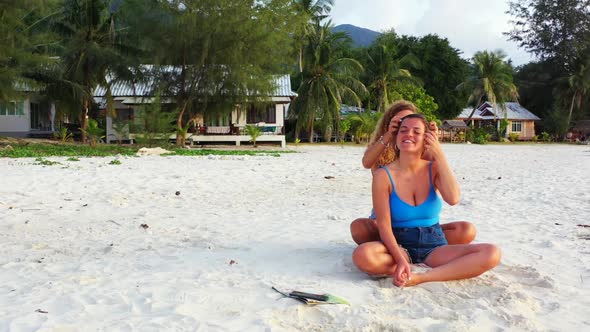 Beautiful ladies sunbathing on tropical island beach wildlife by shallow ocean and white sandy backg