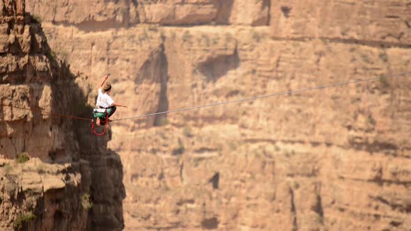 Aerial view of a woman balancing while tightrope walking and slacklining across a canyon.