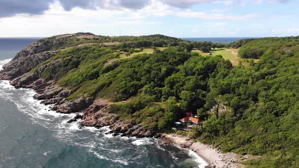 Rising drone view of Kullaberg on sunny/cloudy summer day