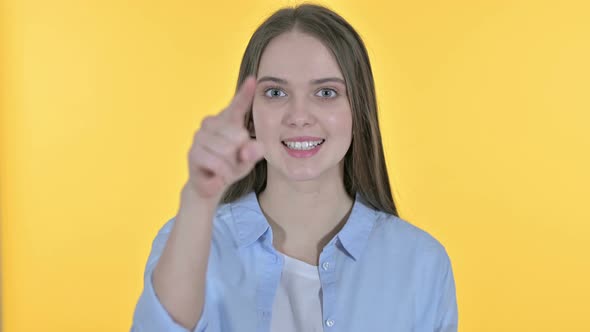 Casual Young Woman Pointing Finger at the Camera, Yellow Background
