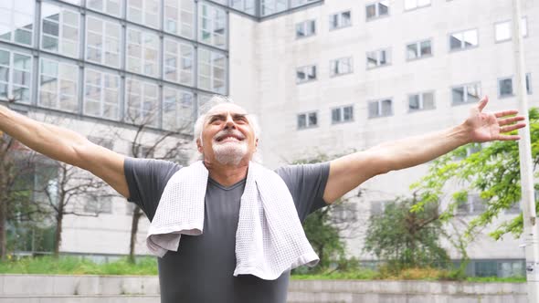 Slow motion shot of smiling senior athletic man with arms raised