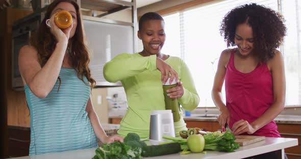 Diverse happy female friends trying healthy drinks at home