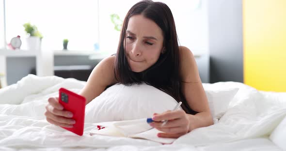 Unhappy Woman Looking Pregnancy Test and Holding Smartphone While Lying on Bed