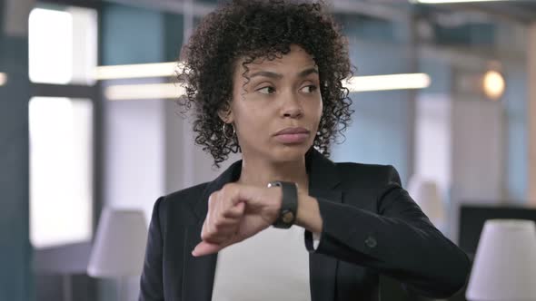 Portrait of Anxious African Businesswoman Waiting for Someone While Checking Her Smart Watch