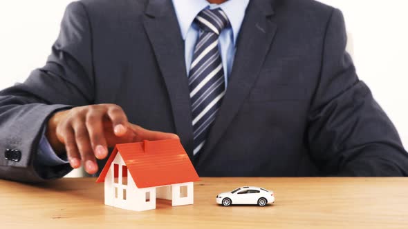 Mid section of businessman with house model and toy car