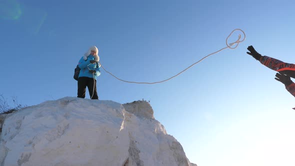 Strong Woman Traveler Helps Man Climber To Climb Mountain on Rope. Teamwork of Tourists. Joyful