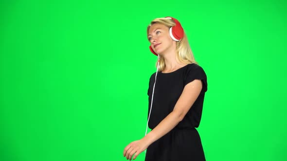 Cheerful Girl Walks in Big Red Headphones and with a Smartphone, Switches Music and Dancing, Chroma