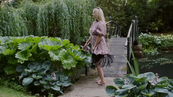 Lovely Woman Fashion Model In Barefoot Looks Back At The Camera As She Walks Through Lush Green Lawn