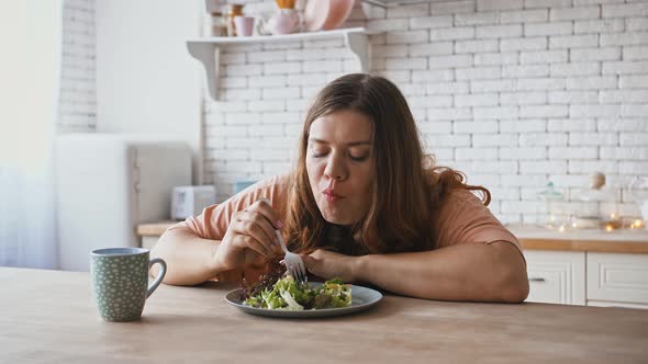 Happy Overweight Woman Eating Salad with Great Pleasure Enjoying Healthy Food at Kitchen Interior