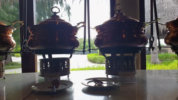 Row of copper pots with delicious food in indian restaurant buffet