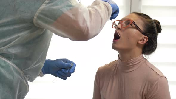 Lab Technician in a Protective Suit Takes a Swab From an Female Patient for Coronavirus.