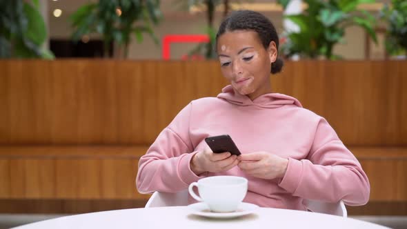 Black African American Woman with Vitiligo Pigmentation Skin Problem Indoor Dressed Pink Hoodie Use