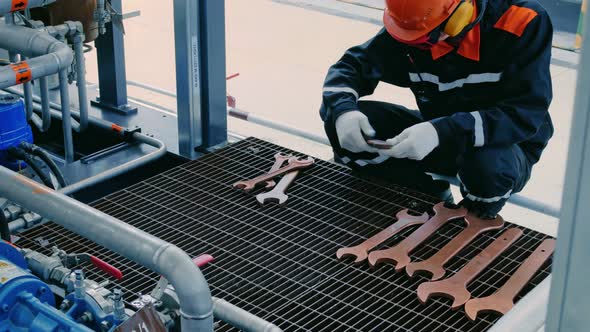 A Mechanic in a Helmet Goggles and Earmuffs Puts Copper Wrenches in Order to Disassemble alt