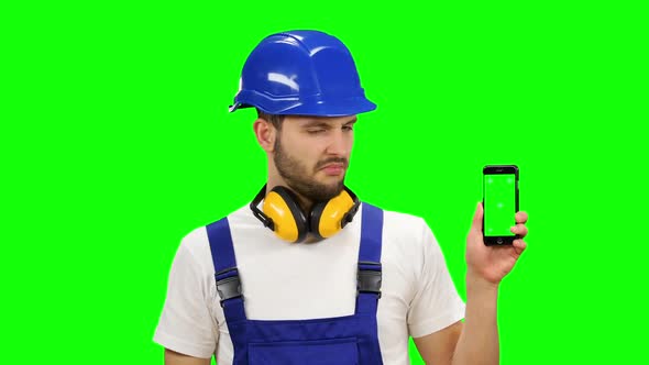 Engineer Is Holding a Phone in His Hand and Showing His Finger Down. Green Screen. Mock Up