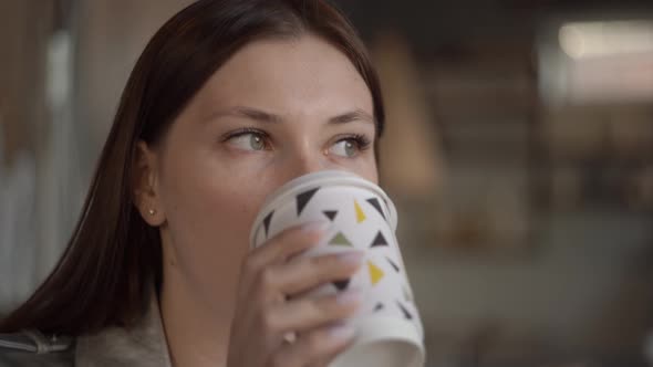 Woman Drinking Coffee in a Cafe While Waiting for a Meeting with a Partner