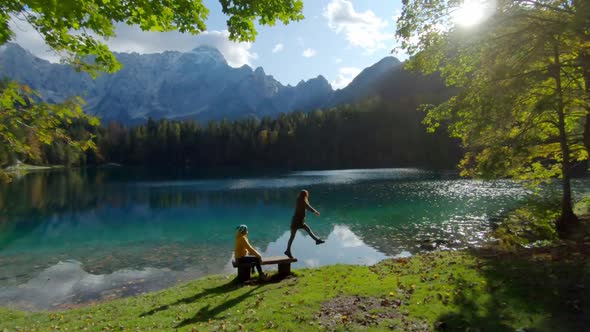 Hiker jumping from a bench at Fusine lake, Italy