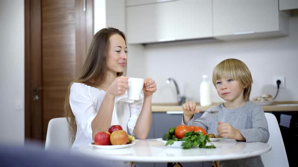 Portrait of Happy Caucasian Mother and Son Having Breakfast at Home in the Morning