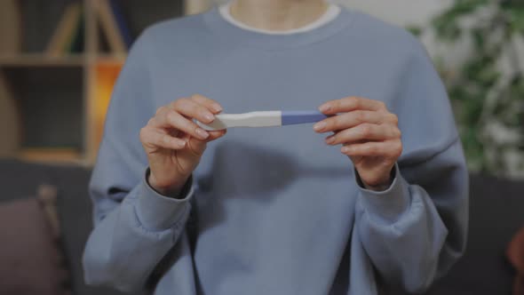 Close Up of Woman Sitting on Couch an Holding Pregnancy Test