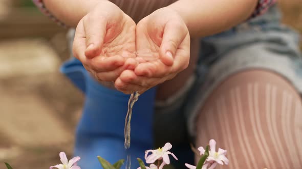 a Little Girl Watering Flowers From the Palms of Her Hands