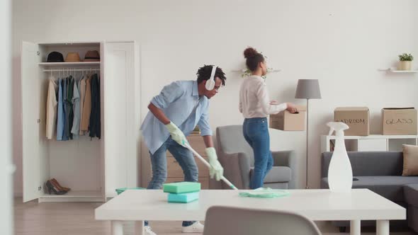 Man Cleaning Floor while Woman Carrying Cardboard Box