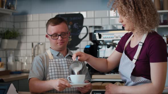 Caucasian man with down syndrome helping waitress in making coffee. Shot with RED helium camera in 8