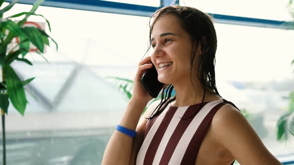 Attractive Girl Resting in a Water Park Talking on a Mobile Phone While Relaxing at the Weekend