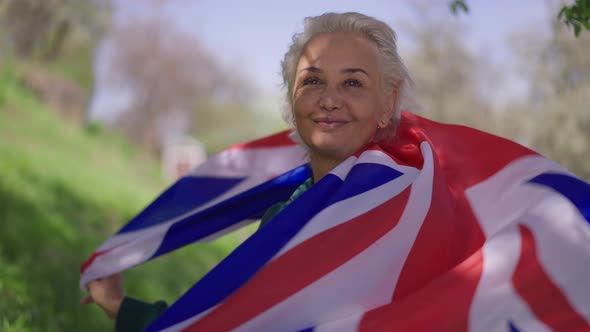 Portrait of Happy Senior Woman Wrapping in British Flag Looking at Camera Smiling