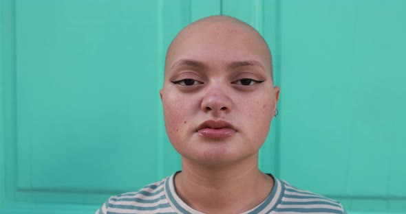 Bald girl looking serious on camera with colorful background