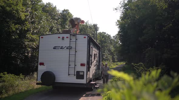 Elderly man climbing down ladder on the back of his RV.