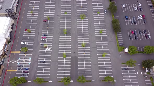 Aerial top-down view of empty parking lot at retail stores and full parking lot at grocery store.