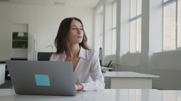 Focused Young Woman is Typing on Laptop