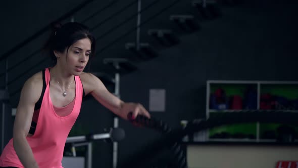 Young Sportive Woman Trains with Ropes in the Gym