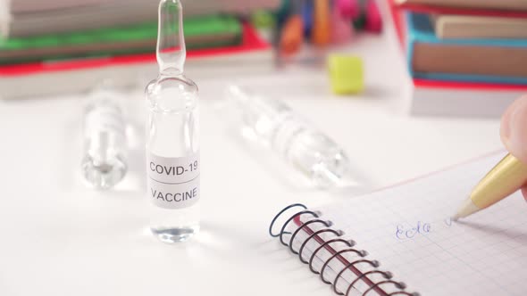 Medical workplace with ampoules with vaccine from COVID-19 and books