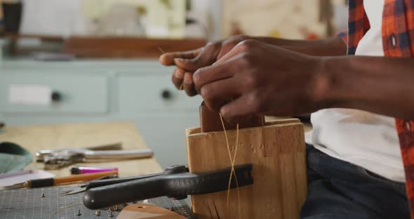 Hands of african american craftsman preparing wallet in leather workshop