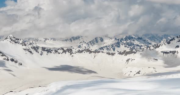 Air Flight Through Mountain Clouds Over Beautiful Snowcapped Peaks of Mountains and Glaciers