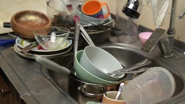 Dirty dishes are put in the sink, which already contains many dirty dishes