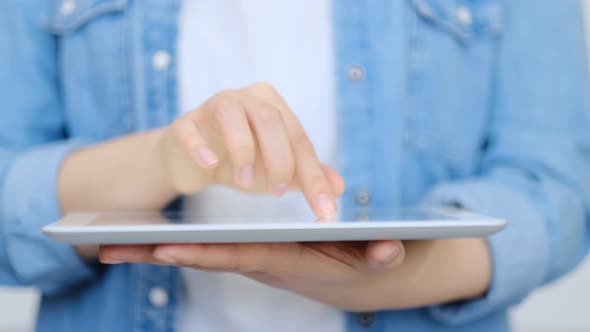 Close Up on the Hand of Young Handsome Woman Pointing and Touching the Screen of a Tablet with Her