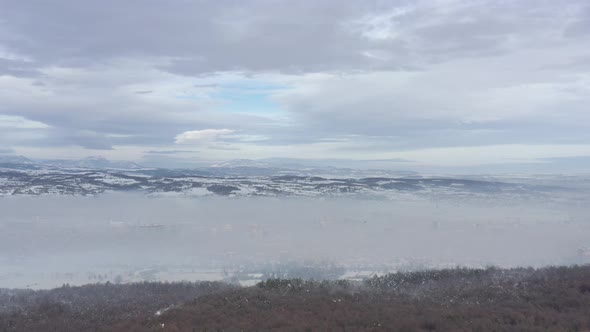 Smog covering the city with mountain ranges in background 4K drone video