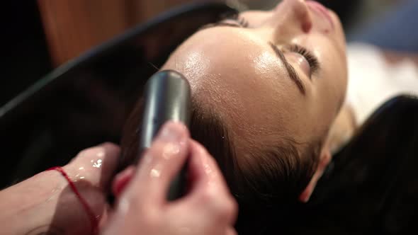 Top View Relaxed Woman in Beauty Salon with Male Tattooed Hands Rinsing Shampoo From Long Hair