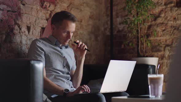 Thoughtful Serious Young Man Student Writer Sit at Home Office Desk with Laptop Thinking of