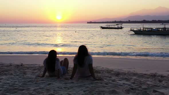 Girls sunbathing on marine coastline beach wildlife by transparent lagoon and white sandy background