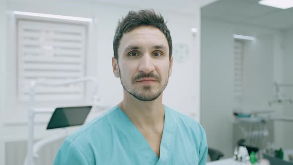 Portrait of Friendly Male Doctor Is Smiling and Looking To the Camera at a Hospital Background