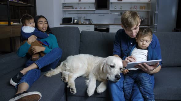 Family Sitting on Couch with Pet Labrador at Home