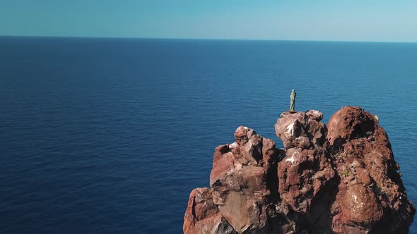 Aerial View on High Rock and Statue on Its Peak in Mediterranean Sea Against Horizon. Blue Sky