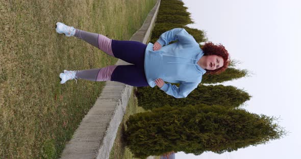 curly red-haired girl tying her shoelaces and twisting her pelvis