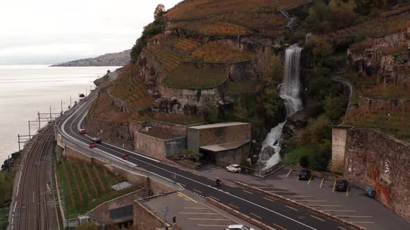 Aerial of waterfall near road and train track near large lake